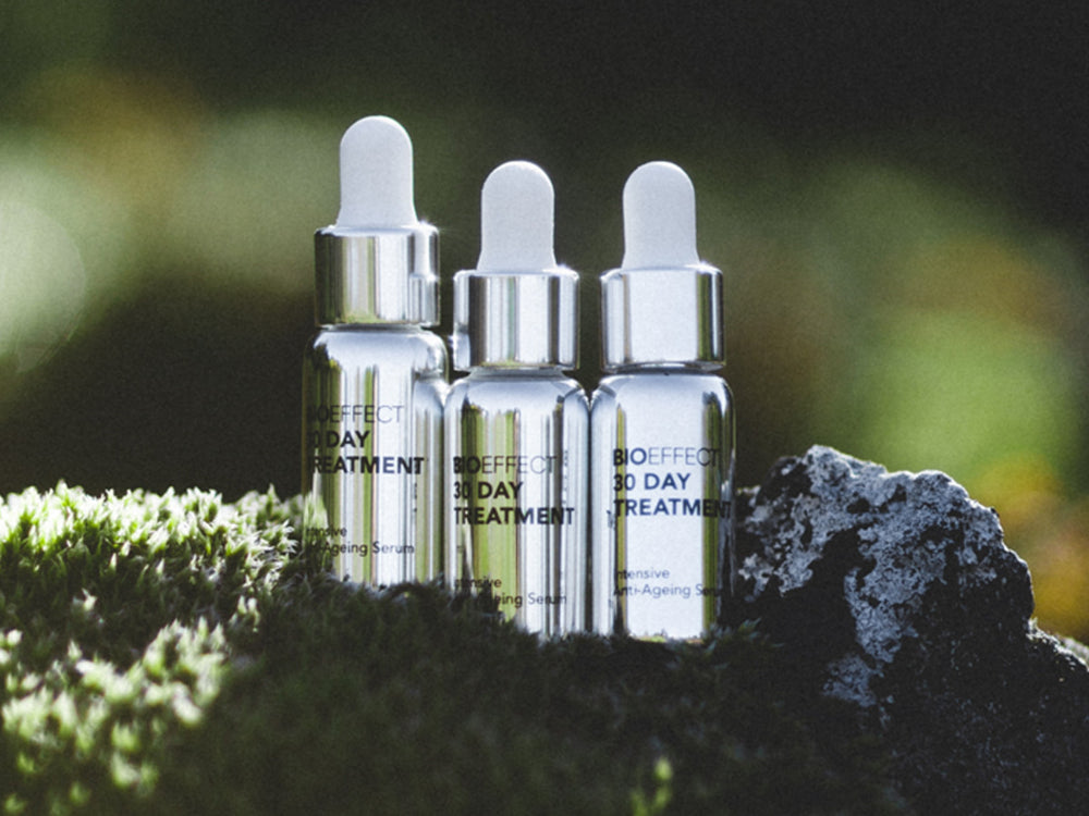 30-Day anti-aging skincare treatment products photographed on moss next to volcanic rock