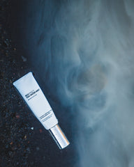 OSA Facial Mist sitting on wet black sand surrounded by mist